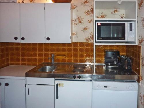 une cuisine avec un évier et un micro-ondes dans l'établissement Bel Apt avec Balcon Sud au Cœur de la Station - FR-1-322-349, aux Orres