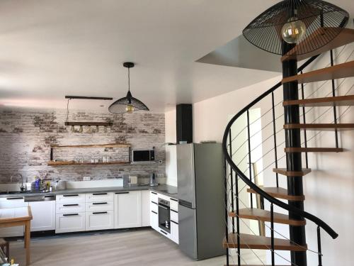 une cuisine avec des placards blancs et un escalier en colimaçon dans l'établissement Maison des rencontres amicales, au Crotoy