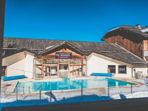 un bâtiment avec une piscine dans la neige dans l'établissement Appartement cosy 6 pers avec piscine, sauna et accès direct aux pistes - Les Orres 1800 - FR-1-322-329, aux Orres