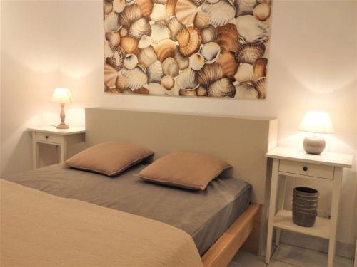 un lit avec deux oreillers et un tableau au mur dans l'établissement Quiberon - Appartement 2 pièces - 4 pers, balcon, parking - FR-1-478-77, à Quiberon