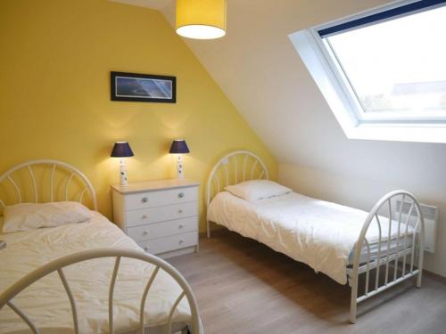 Cette chambre comprend 2 lits dans une chambre dotée de murs jaunes et d'une fenêtre. dans l'établissement Villa Belz, 5 pièces, 8 personnes - FR-1-479-22, à Belz