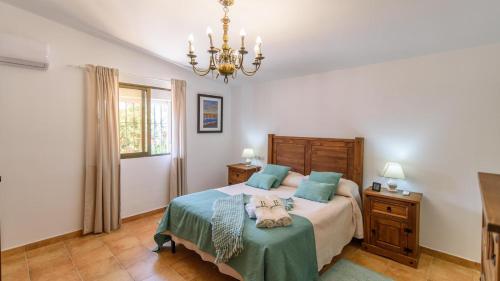 sypialnia z łóżkiem i żyrandolem w obiekcie Casa rural cerca de Aracena Castillo de las Guardas by Ruralidays w Sewilli