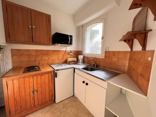 Una pequeña cocina con gabinetes de madera y un fregadero. en Charmant T1 Bis à Cambo-les-Bains avec balcon, ascenseur et parking - FR-1-495-31, en Cambo-les-Bains