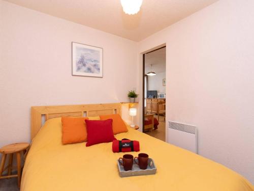 - une chambre dotée d'un lit jaune avec des oreillers rouges et oranges dans l'établissement Appartement Saint-Lary-Soulan, 2 pièces, 4 personnes - FR-1-296-281, à Saint-Lary-Soulan