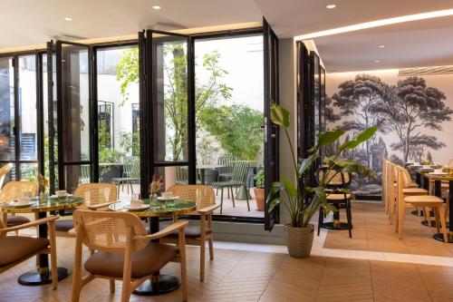 a restaurant with tables and chairs and large windows at H&ocirc;tel La Canop&eacute;e in Paris