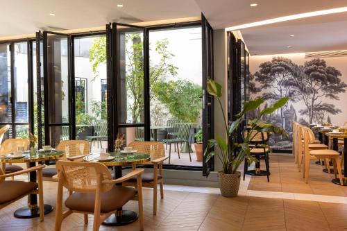 a restaurant with tables and chairs and large windows at Hôtel La Canopée in Paris