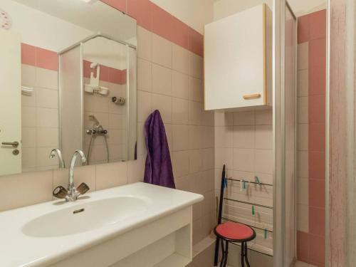 La salle de bains est pourvue d'un lavabo et d'un tabouret rouge. dans l'établissement 2 pièces, parking, balcon sud, proche télécabine - Briançon - FR-1-330C-66, à Briançon