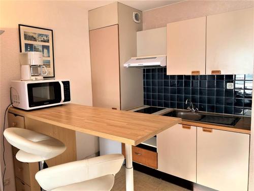 une petite cuisine avec une table en bois et un four micro-ondes dans l'établissement Studio cosy à Quiberon avec parking et animaux admis, face à la mer - FR-1-478-87, à Quiberon
