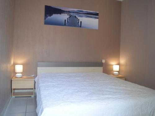 une chambre avec un lit blanc avec deux tables de nuit dans l'établissement Appartement 3 Pièces à Saint-Cyprien : 6 Couchages, Piscine, Terrasse, Parking et WIFI - FR-1-225D-68, à Saint Cyprien Plage