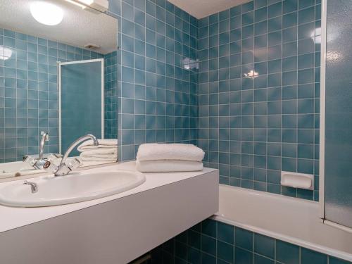La salle de bains est pourvue de carrelage bleu, d'un lavabo et d'un miroir. dans l'établissement Carnac: Studio cosy 23m² près plage, parking, animal admis - FR-1-477-132, à Carnac