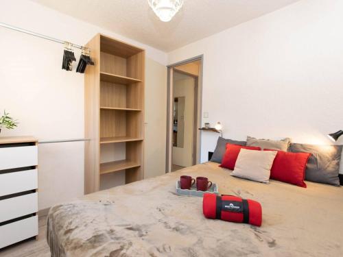 une chambre avec un grand lit avec des oreillers rouges dans l'établissement Appartement cosy 4 pers avec parking, proche centre, commerces et téléphérique - FR-1-296-279, à Saint-Lary-Soulan
