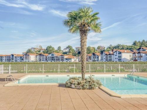 a palm tree sitting next to a swimming pool at Appartement Urrugne, 2 pièces, 4 personnes - FR-1-4-567 in Urrugne