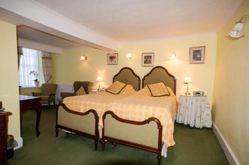 a bedroom with a bed with two chairs in it at Bishopsgate House Hotel in Beaumaris
