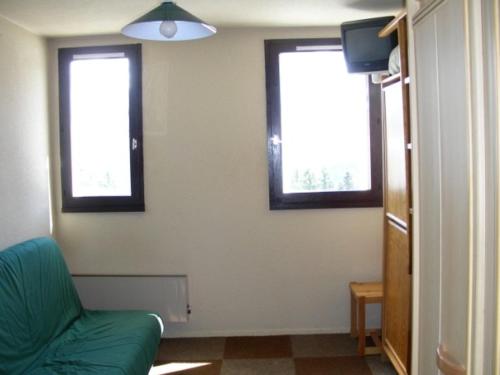 - un salon avec deux fenêtres et un canapé vert dans l'établissement Appartement Le Pleynet, 1 pièce, 3 personnes - FR-1-557A-18, à La Ferrière