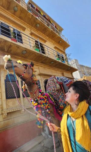 a woman standing next to a horse next to a building at Blue Eye Hostel in Jaisalmer
