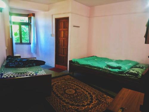 a room with two beds and a window and a door at Hotel Sakura in Darjeeling