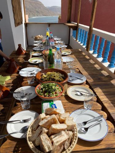 a long wooden table with plates of food and bread at Imsouanegreenwave in Imsouane