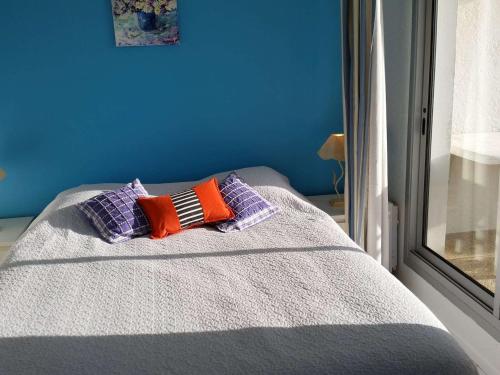 - un lit avec 2 oreillers et un mur bleu dans l'établissement Appartement lumineux avec balcon, parking et animaux acceptés - FR-1-494-66, à Royan