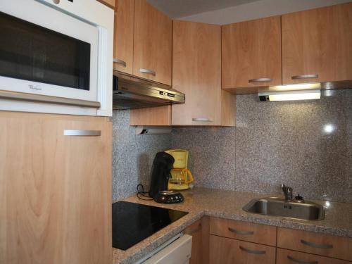 une cuisine avec un évier et un micro-ondes dans l'établissement Charmant 2 pièces rénové, 6 pers, balcon, accès direct pistes, au cœur des Orres - FR-1-322-384, aux Orres