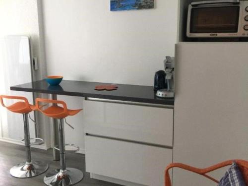 La cuisine est équipée d'un comptoir, d'un réfrigérateur et de tabourets. dans l'établissement Appartement lumineux avec balcon, parking et animaux acceptés - FR-1-494-66, à Royan