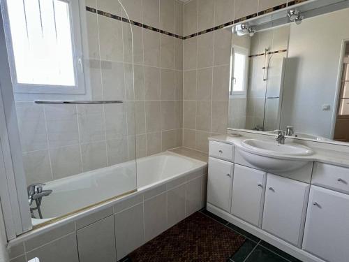 een witte badkamer met een wastafel, een bad en een spiegel bij Appartement Cambo-les-Bains, 2 pièces, 2 personnes - FR-1-495-82 in Cambo-les-Bains