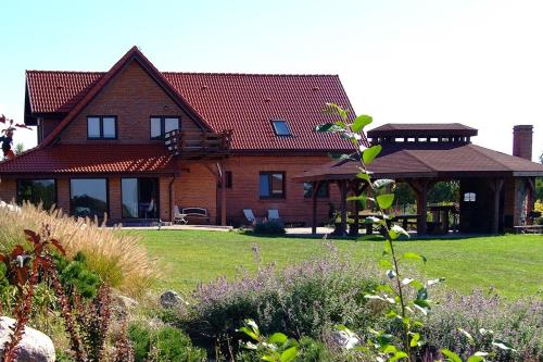a large brick house with a gazebo at Mazury całoroczny dom nad jeziorem do wynajęcia z własną linią brzegową in Pasym