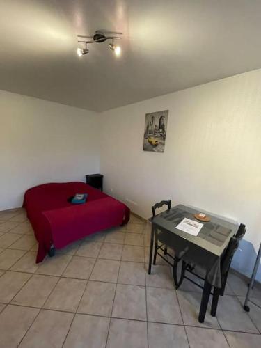 um quarto com uma cama vermelha e uma mesa em Le passage em Paroy-sur-Tholon