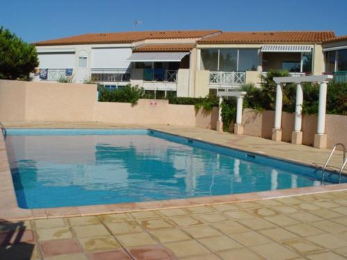 une piscine devant une maison dans l'établissement T2 climatisé en rez-de-jardin avec piscine, parking, et terrase. Plage à 450m, WiFi gratuit. - FR-1-607-52, au Cap d'Agde