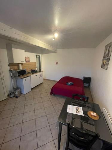 uma sala de estar com uma mesa e uma cama vermelha em Le passage em Paroy-sur-Tholon