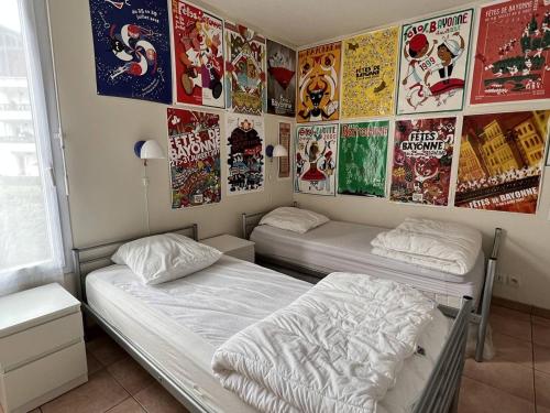 dwa łóżka w pokoju z plakatami na ścianie w obiekcie Appartement Cambo-les-Bains, 3 pièces, 4 personnes - FR-1-495-20 w mieście Cambo-les-Bains