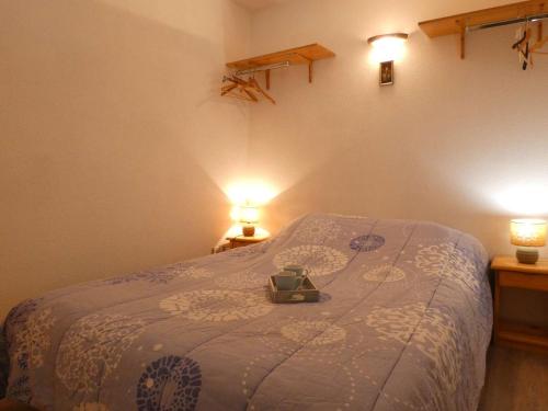 a bedroom with a bed with a blue blanket and two lights at Appartement Saint-Lary-Soulan, 2 pièces, 4 personnes - FR-1-457-244 in Saint-Lary-Soulan