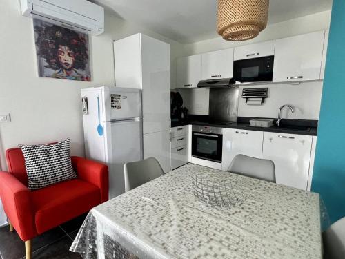une cuisine avec une table et une chaise rouge dans l'établissement Charmant T2, balcon, parking, ascenseur, internet - Itxassou - FR-1-495-47, à Itxassou