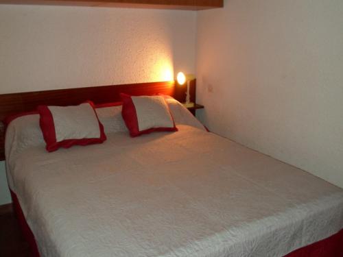 une chambre avec un lit avec des oreillers rouges et blancs dans l'établissement Appartement cosy avec balcon près des thermes, parking, animaux admis, non-fumeur, Balaruc-les-Bains - FR-1-503-33, à Balaruc-les-Bains