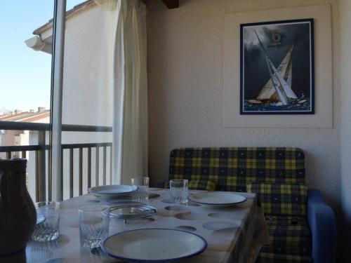 une table avec des assiettes et des verres au-dessus dans l'établissement Locations Saint-Cyprien: Appartement 2 pièces avec parking, terrasses, et loggia - FR-1-225D-35, à Saint Cyprien Plage