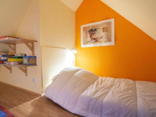 un letto in una stanza con una parete arancione di Chalet triplex pour 7 pers. avec terrasse, parking, proche télécabine et commerces - FR-1-401-178 a Cauterets