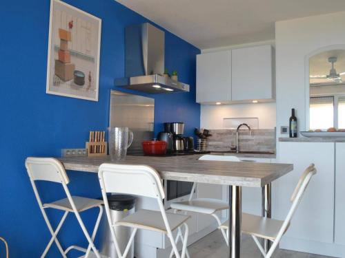 une cuisine avec des murs bleus et un comptoir avec des chaises blanches dans l'établissement Appart T2 avec terrasse, parking, WIFI, animaux admis - FR-1-225C-31, à Banyuls-sur-Mer