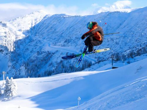 un homme volant à travers l'air en faisant du ski dans l'établissement Appartement de charme avec grande terrasse et vue dégagée - FR-1-505-35, à Notre-Dame-de-Bellecombe