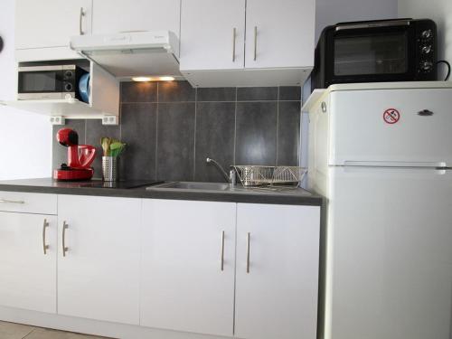 La cuisine blanche est équipée d'un évier et d'un réfrigérateur. dans l'établissement Charmant T1 avec Terrasse et Clim à 100m des Thermes - Wifi, Lave-linge, et Cuisine Équipée - FR-1-553-16, à Balaruc-les-Bains