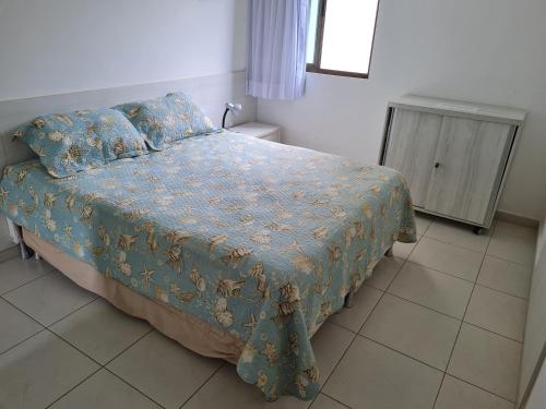 a bedroom with a bed with a blue comforter and a cabinet at Flat Praia Dos Carneiros in Tamandaré