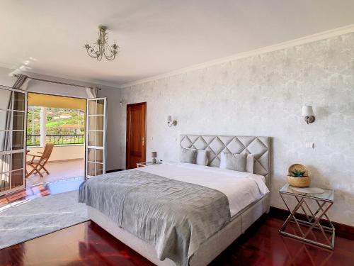 a bedroom with a large bed and a balcony at Villa Baradaye by LovelyStay in Estreito da Calheta