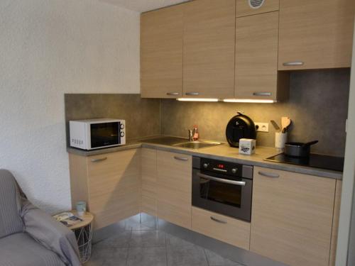 La cuisine est équipée de placards en bois, d'un évier et d'un four micro-ondes. dans l'établissement Bel appartement 2 pièces avec WIFI, parking, au pied des pistes de ski à Montgenèvre - FR-1-266-145, à Montgenèvre