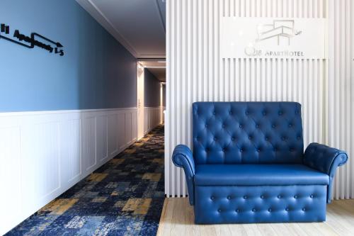 a blue chair in a room with a hallway at Q18 ApartHotel in Bydgoszcz