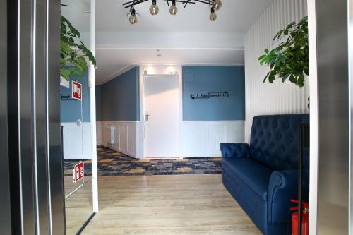 a living room with a blue couch and a hallway at Q18 ApartHotel in Bydgoszcz