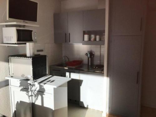 une cuisine avec des armoires blanches et un micro-ondes dans l'établissement Studio Cabine 4 Pers - Pied des Pistes - Parking Couvert - Balcon Sud - TV - Animaux Ok - FR-1-404-212, à La Mongie
