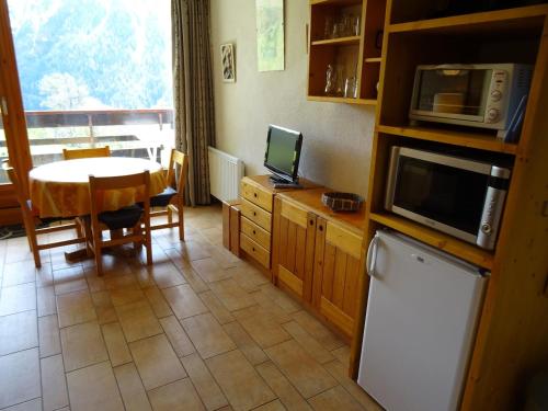 une cuisine avec une table et un four micro-ondes ainsi qu'une salle à manger dans l'établissement Studio cosy 4 personnes proche commerces et pistes, animaux acceptés - FR-1-411-641, à Peisey-Nancroix