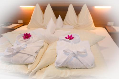 een bed met witte handdoeken en roze bloemen erop bij Pension Felseneck in San Leonardo in Passiria