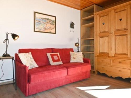 a red couch in a living room with a book shelf at Studio Montgenèvre, 1 pièce, 4 personnes - FR-1-266-159 in Montgenèvre