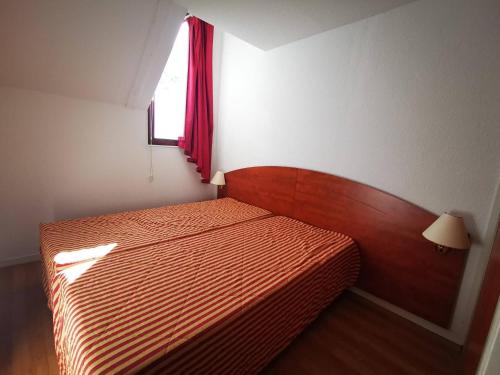 une chambre avec un lit avec une couverture rouge et une fenêtre dans l'établissement Duplex au calme 7 couchages, balcon sud, parking, piscine couverte, fitness, proche pistes et centre - FR-1-404-244, à La Mongie