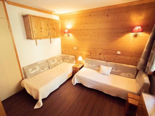 a room with two beds and a wooden wall at Studio divisible, balcon, animaux acceptés, casier à skis, linge de lit inclus - FR-1-291-839 in Valmorel