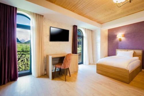 um quarto com uma cama, uma secretária e uma janela em Hotel Mestia Inn em Mestia